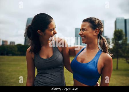 Wir lieben es, zusammen zu passen. Eine kurze Aufnahme von zwei attraktiven jungen Sportlerinnen, die gemeinsam in der Stadt draußen arbeiten. Stockfoto