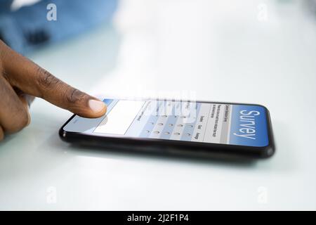 Nahaufnahme der Person ausfüllen Online Umfrage Formular auf Handy Stockfoto