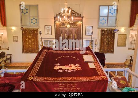 Roter Stoff, der den tora-Leseport in der zentralen bima mit der Arche im Hintergrund bedeckt. In der Synagoge von Algazi in Izmir, Türkei. Stockfoto