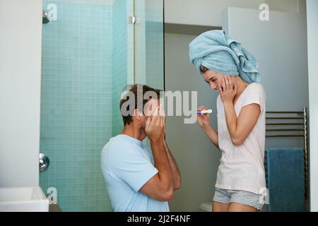 Überraschen Sie, dass Sie ein Vater sein werden. Aufnahme eines jungen Paares, das nach einem Schwangerschaftstest im Badezimmer glücklich aussieht. Stockfoto