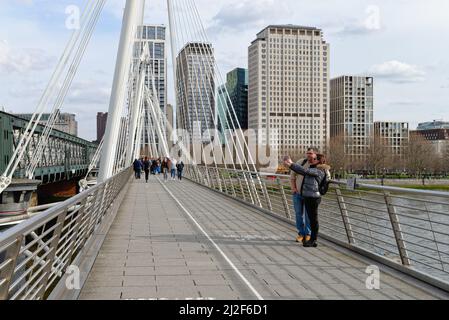 Ein junges Paar Touristen, die ein Selfie auf der Golden Jubilee Fußgängerbrücke über die Themse machen, Charing Cross im Zentrum von London England Stockfoto