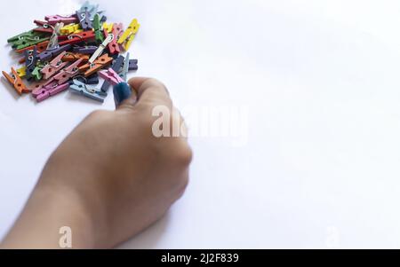 Eine weibliche Hand mit Stapel von Mini-farbigen Wäscheklammern isoliert auf einem weißen Hintergrund mit Kopierraum Stockfoto