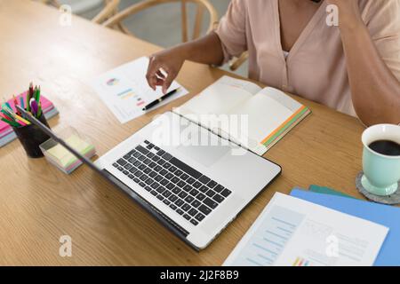 Mittelteil einer afroamerikanischen Freiberuflerin mit mittlerem Erwachsenen und Laptop am Schreibtisch Stockfoto