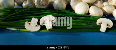 In Scheiben geschnittene ​​champignons und ganze Pilze auf grünen Zwiebeln. Zutaten. Die Produkte sind frisch. Rohkost. Stockfoto