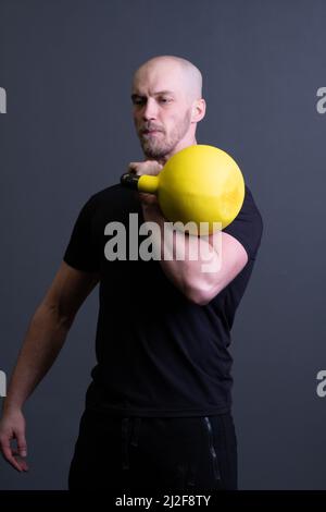 Typ mit einem gelben Kettlebell Gym anonymen Workout-Mann, am Nachmittag fit Lifestyle für das Training und Boden sportliche, Südost-Fitness. Mann runter Stockfoto