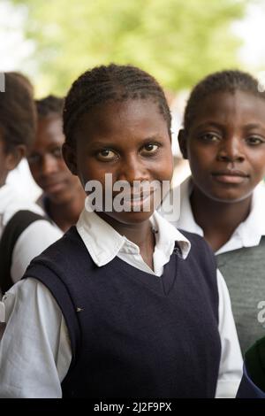 Afrikanische Schülerinnen der Sekundarstufe lächeln zusammen in ihrem Schulhof in der Region Oshana, Namibia, im südlichen Afrika. Stockfoto