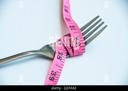 Gabel mit Messband gebunden. Gewichtsverlust und Fitness-Konzept Stockfoto