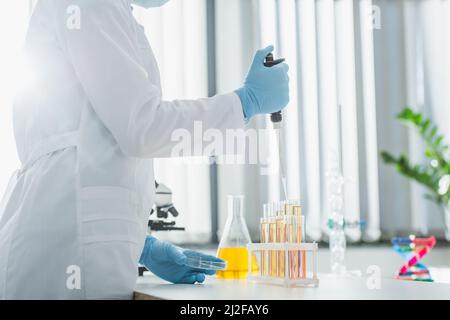 Teilansicht des Genetikers in weißer Schicht, der mit Mikropipette und Reagenzgläsern arbeitet, Stockbild Stockfoto