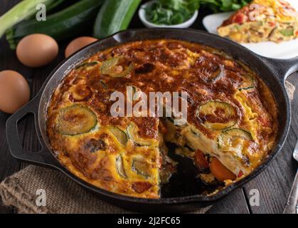 Frittata mit Gemüse. Im Ofen gebacken und hausgemacht gekocht. Serviert in einer rustikalen gusseisernen Pfanne Stockfoto