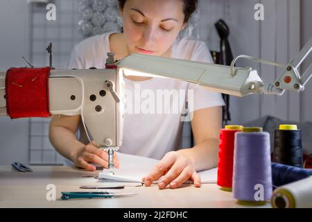 Eine Nähmaschine, für die der Schneidermeister im weichen Fokus arbeitet. Stockfoto