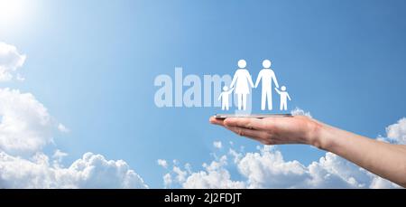 Hand auf Himmel Hintergrund hält Familie Symbol.Gesundheitswesen und Lebensversicherung Konzept.Vater, Mutter, Tochter und Sohn Stockfoto