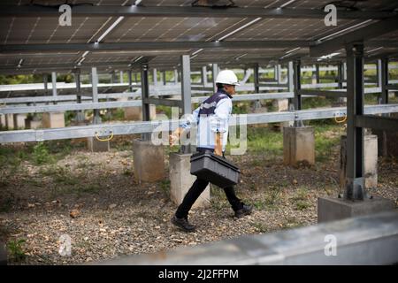 Ein Elektrotechniker betreibt Ausrüstung in einem Solarkraftwerk auf der Insel Karampuang, Indonesien, Asien. Stockfoto