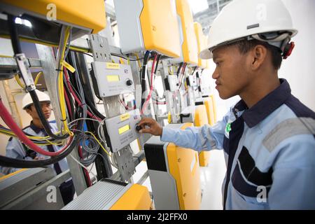 Ein Elektrotechniker betreibt Ausrüstung in einem Solarkraftwerk auf der Insel Karampuang, Indonesien, Asien. Stockfoto