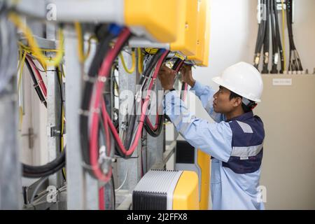 Ein Elektrotechniker betreibt Ausrüstung in einem Solarkraftwerk auf der Insel Karampuang, Indonesien, Asien. Stockfoto