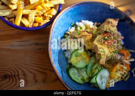 Hähnchenspieß und Gemüse in einer Schüssel mit Pommes auf dem Hintergrund Stockfoto