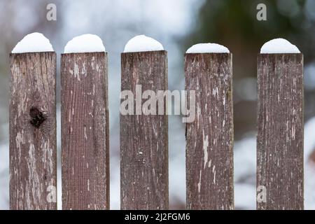 Fragment eines alten Holzzauns mit Schnee, Nahaufnahme mit selektivem Fokus Stockfoto