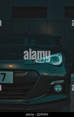 Die vertikale Aufnahme eines schwarzen Porsche Cayman auf einem Parkplatz Stockfoto