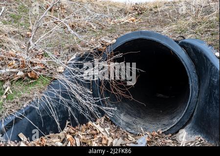 HDPE-Drainage unter einer Straßeneinfahrt. Das Rohr dient zur Förderung von Regenwasser zwischen Gräben. Stockfoto