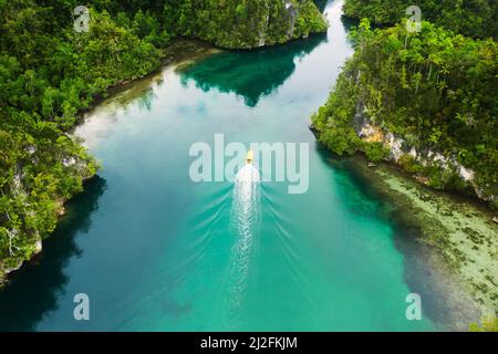 Es gibt so viel Schönheit hier gefunden. Aufnahme eines Bootes, das durch einen Kanal entlang der Raja Ampat-Inseln in Indonesien segelt. Stockfoto