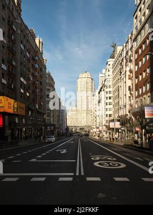 Perspektivischer Blick auf die leere Gran Via mit Blick auf die Plaza de España am Morgen. Das Telefónica-Gebäude ist im Hintergrund zu sehen. Stockfoto