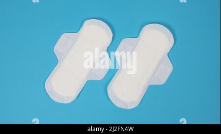 Damenbinden auf blauem Hintergrund. Draufsicht. Saugfähige Pads, die von Frauen zur Aufnahme von Menstruationsblut getragen werden. Bequeme weiße Sanitärservietten arrangiert Stockfoto