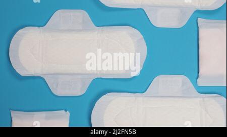Damenbinden auf blauem Hintergrund. Draufsicht. Saugfähige Pads, die von Frauen zur Aufnahme von Menstruationsblut getragen werden. Bequeme weiße Sanitärservietten arrangiert Stockfoto