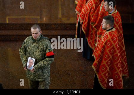 Non Exclusive: MUKACHEVO, UKRAINE - 1. APRIL 2022 - Ein Militärangehöriger hält das Porträt des 18-jährigen Viktor Karytschak, eines Soldaten des mechanisierten Kampfes Stockfoto