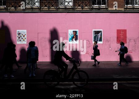 London, Großbritannien. 26. März 2022. Silhouettierte Menschen passieren eine Baustelle auf der Oxford Street. Bild: Stephen Chung / Alamy Stockfoto