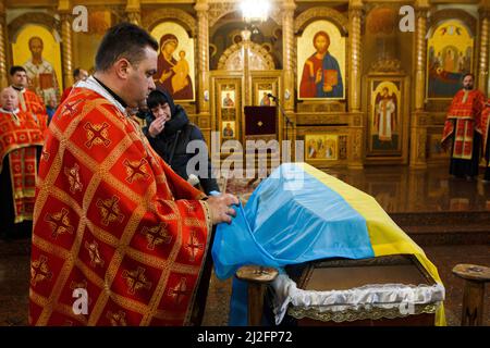 Nicht exklusiv: MUKACHEVO, UKRAINE - 1. APRIL 2022 - Ein Priester steht am Sarg des 18-jährigen Viktor Karytschak, einem Soldaten des mechanisierten Bataillons Stockfoto