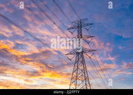 Nahaufnahme der Hochspannungsmaste, Hintergrund des Hochspannungsturms bei Sonnenuntergang. Stockfoto