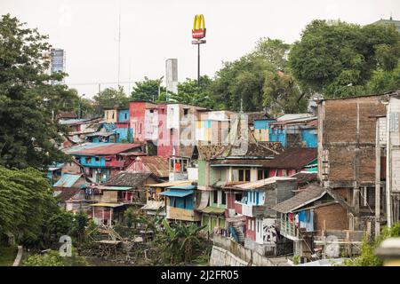 Ein McDonald's-Schild mit den goldenen Bögen ragt über überfüllten, farbenfrohen Slumhäusern in Yogyakarta (Jogjakarta), Indonesiens zweitgrößter Stadt, auf. Stockfoto