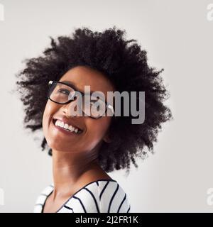 So glücklich und sorglos wie möglich. Studioaufnahme einer attraktiven und glücklichen jungen Frau, die vor grauem Hintergrund eine Brille trägt. Stockfoto