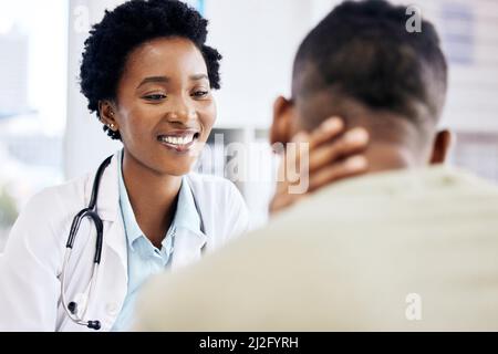 Wie haben Sie sich gefühlt? Eine kleine Aufnahme einer attraktiven jungen Ärztin, die sich in ihrem Büro mit einem nicht erkennbaren männlichen Patienten beraten lässt. Stockfoto