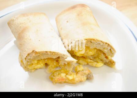 Nahaufnahme eines Frühstücksburritos auf einem weißen Teller Stockfoto