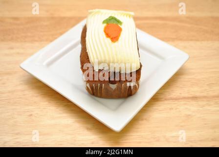 Ein Mini-Karottenkuchen mit Matten, serviert auf einem kleinen weißen Teller Stockfoto