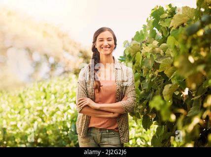 Ich liebe es, den ganzen Tag in der Sonne zu arbeiten. Porträt einer fröhlichen jungen Farmerin, die auf den Feldern ihres Bauernhofes posiert. Stockfoto