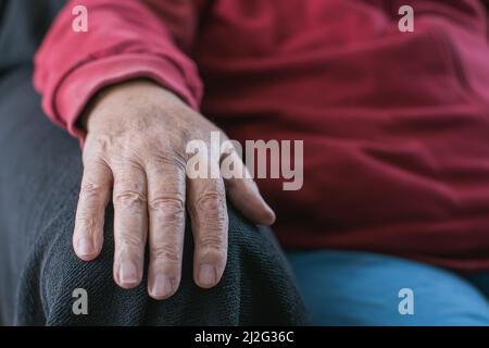 Die Hand eines alten Menschen ruht auf dem Sessel Stockfoto
