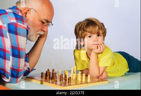 Großvater und Enkel spielen Schach. Opa lehrt sein Enkel Schach zu spielen. Schachmatt. Stockfoto