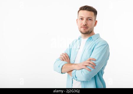 Porträt eines fröhlichen jungen Mannes in einem weißen T-Shirt auf weißem Hintergrund. Der Typ steht und schaut auf die Kamera und lächelt. Stockfoto