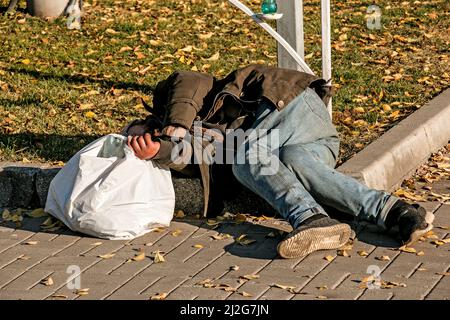 Dnipropetrovsk, Ukraine - 10.31.2021: Ein Obdachloser schläft auf dem Bürgersteig auf der Straße. Stockfoto