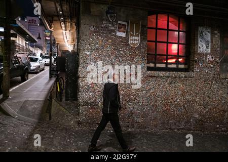 Seattle, USA. 31. März 2022. The Gum Wall by Pike Place Market mit einer Person, die nachts vorbeikommt, nachdem die Zwangsbeschränkungen aufgehoben wurden. Stockfoto