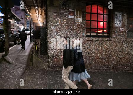 Seattle, USA. 31. März 2022. The Gum Wall by Pike Place Market mit Menschen, die nachts vorbeikommen, nachdem die Zwangsbeschränkungen aufgehoben wurden. Stockfoto