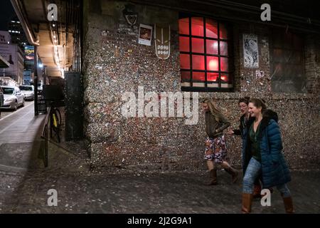 Seattle, USA. 31. März 2022. The Gum Wall by Pike Place Market mit Menschen, die nachts vorbeikommen, nachdem die Zwangsbeschränkungen aufgehoben wurden. Stockfoto