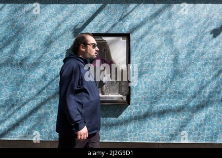 Seattle, USA. 31. März 2022. Menschen, die an einem verwüsteten Schild in Cinerama in Belltown vorbeikommen. Stockfoto