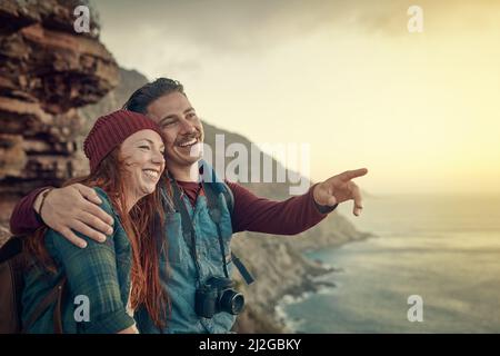 Ist das, wo wir angefangen haben. Eine kurze Aufnahme eines liebevollen jungen Paares, das die Aussicht von einem Berggipfel aus betrachtet. Stockfoto