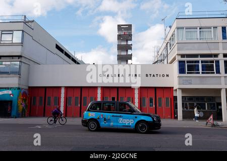 London, Greater London, England, März 12 2022: Taxi und Radfahrer vor der Feuerwache auf der Kings Road in Chelsea. Stockfoto