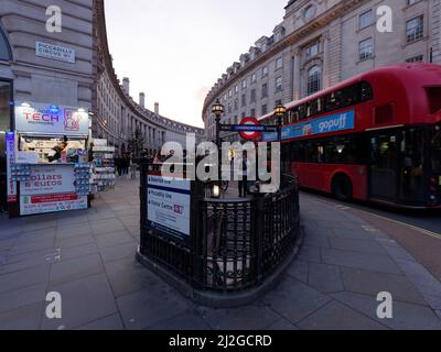 London, Greater London, England, März 12 2022: Piccadilly Circus U-Bahnstation und Kiosk im Vordergrund mit einem Bus auf der Regent Street dahinter. Stockfoto