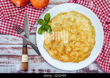 Blick von oben auf ein spanisches Kartoffelomelett auf einem rustikalen Tisch. Traditionelle Aussicht. Stockfoto