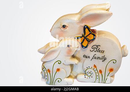 Osterdekor von Mutter und Baby Kaninchen - kleine riecht Schmetterling auf größeren und Worte segnen unsere Familie sind darauf geschrieben - isoliert auf Whi Stockfoto