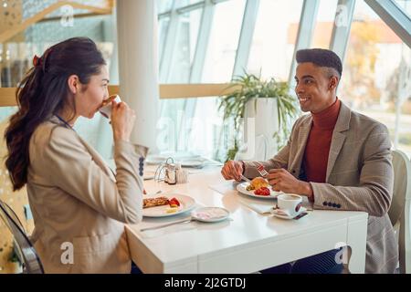 Ein junger Geschäftsmann plaudert mit seiner jungen Kollegin während einer Mittagspause in entspannter Atmosphäre in der Kantine. Unternehmen, Mitarbeiter, Unternehmen Stockfoto